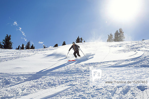 Reifer Mann fährt mit Skiern den sonnenbeschienenen schneebedeckten Berg hinunter  Steiermark  Tirol  Österreich