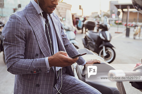 Businessman using smartphone by motorcycle