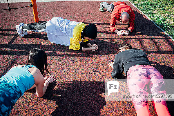 Calisthenics-Kurs im Freiluft-Gymnastikraum  junge Frauen und Männer beim Üben der Yogastellung