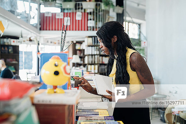 Junge Geschäftsfrau betrachtet Bücher im Buchladen