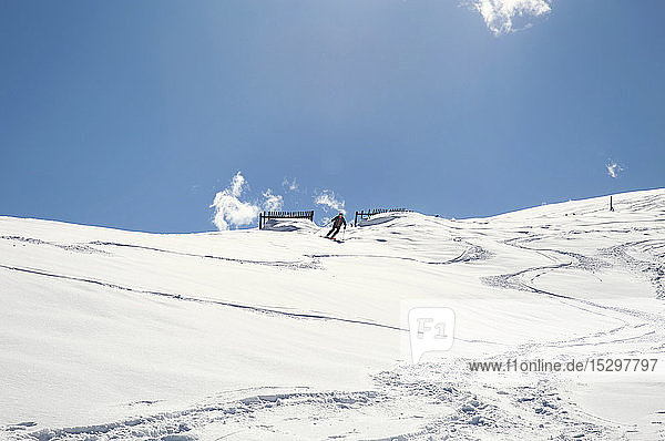 Mature man skiing down snow covered mountain  distant low angle view  Styria  Tyrol  Austria