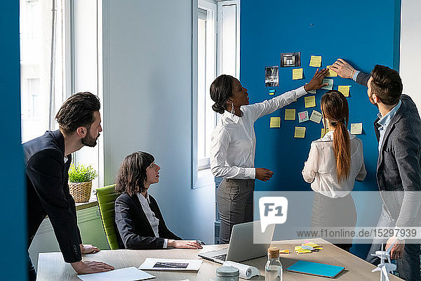 Young male and female business creative team having brainstorming office meeting with sticky notes