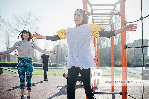 Calisthenics class at outdoor gym  young women jumping with arms outstretched