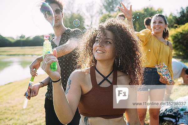Gruppe von Freunden spielt mit Blasenpistole im Park