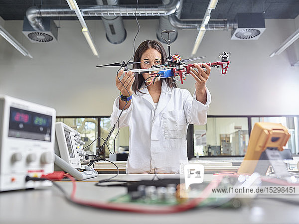 Im Forschungslabor arbeitende Technikerin  die eine Drohne hält
