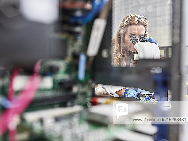 Weibliche Technikerin  die im Forschungslabor mit dem Mikroskop arbeitet
