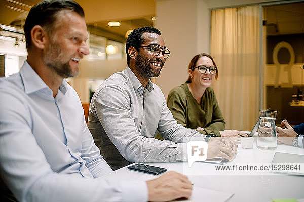 Sales executives smiling during business meeting at conference table in office