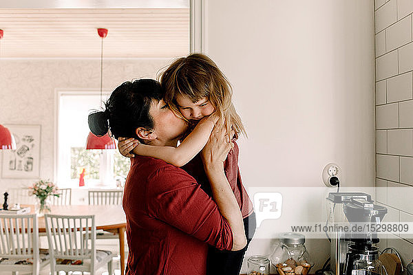 Seitenansicht einer Mutter  die ihre traurige Tochter zu Hause küsst