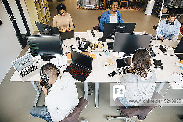 Schrägansicht von IT-Fachleuten  die im kreativen Büro am Schreibtisch sitzen