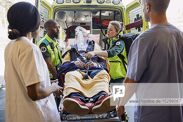 Mediziner betrachten Sanitäter mit Patient gegen Krankenwagen