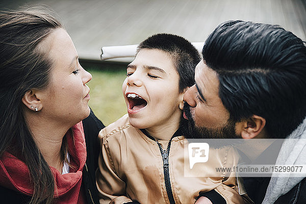 Vater küsst glücklichen Sohn  der seine Mutter im Hof ansieht