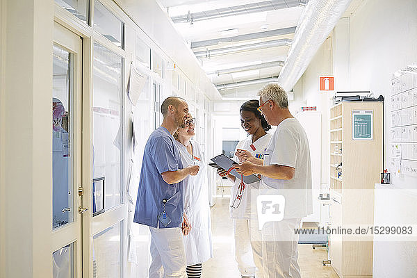 Lächelndes Gesundheitspersonal diskutiert im Krankenhaus auf dem Flur