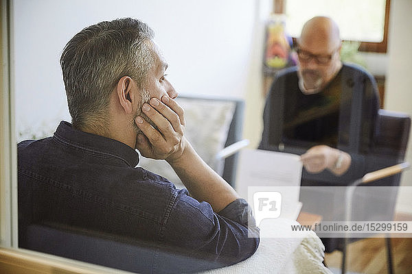 Nachdenklicher männlicher Patient sitzt bei Therapie-Workshop