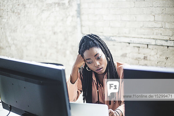 Hochwinkelansicht einer jungen weiblichen Computerhackerin  die am Schreibtisch im Büro kodiert