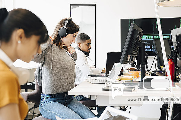 Seitenansicht von Computerprogrammierern  die am Schreibtisch arbeiten  während sie im Büro sitzen
