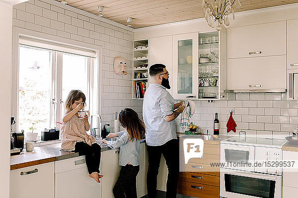 Vater und Tochter arbeiten am Tresen  während das Mädchen in der Küche isst