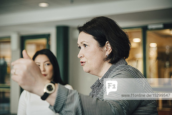 Zuversichtliche Geschäftsfrau gestikuliert beim Erklären während einer Konferenzveranstaltung im Amt