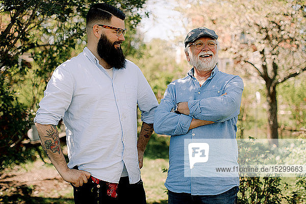 Lächelnder älterer Vater und Sohn stehen im Hof