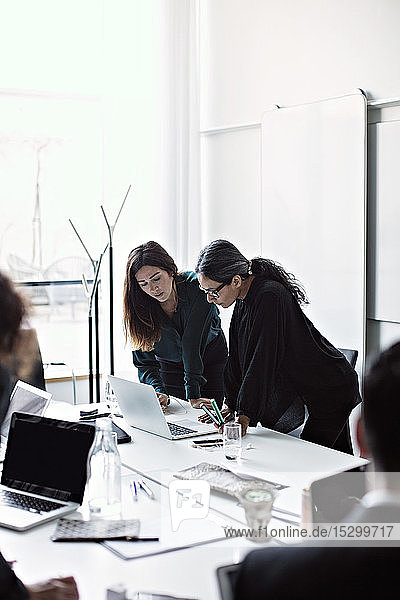 Geschäftsfrauen arbeiten über Laptop am Konferenztisch im Sitzungssaal