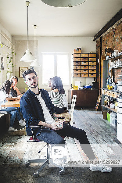 Porträt eines selbstbewussten jungen männlichen IT-Experten  der in einem kreativen Büro auf einem Stuhl sitzt