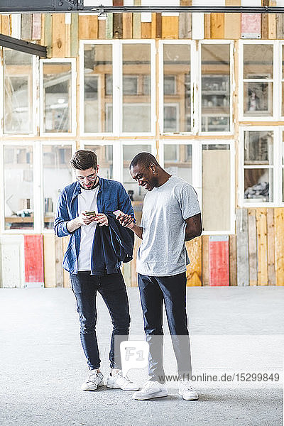 Textnachrichten lächelnder Geschäftsleute in voller Länge mit Mobiltelefonen am kreativen Arbeitsplatz