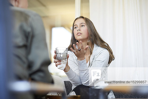 Depressed teenager talking to therapist while drinking water at workshop