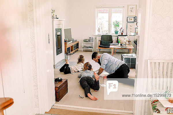 Mid adult man drawing with daughters while resting in living room at home