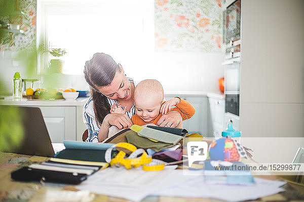 Smiling mother playing with loving daughter while balancing work life at home