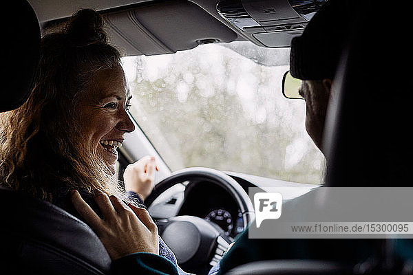 Fröhliche Frau unterhält sich mit einem Freund  während sie im Auto unterwegs ist
