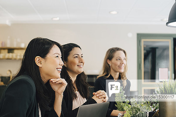 Lächelnde Geschäftsfrauen sitzen in einer Sitzung am Konferenztisch