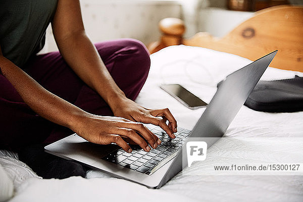 Niedriger Anteil junger Frauen  die zu Hause auf dem Bett sitzen und einen Laptop benutzen