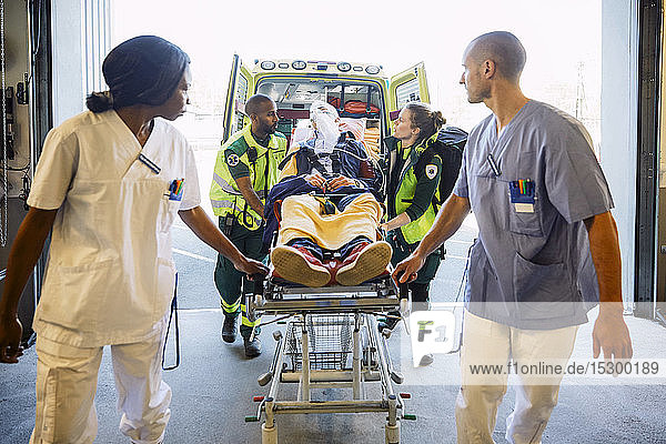 Healthcare workers pushing patient on gurney in hospital