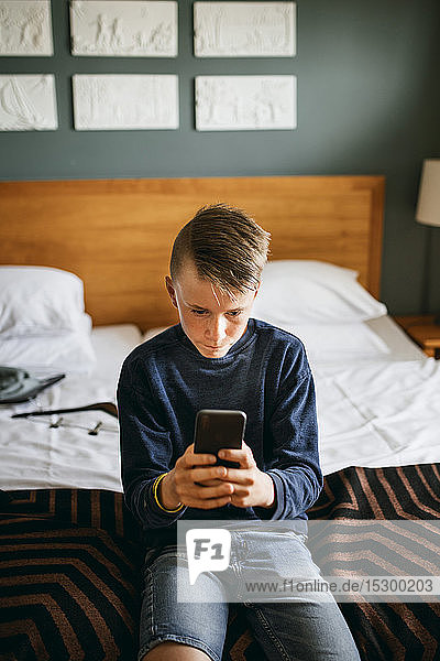 Boy in hotel room checking his mobile