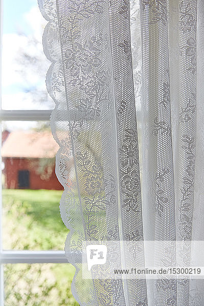 White lacy curtain hanging from window at home