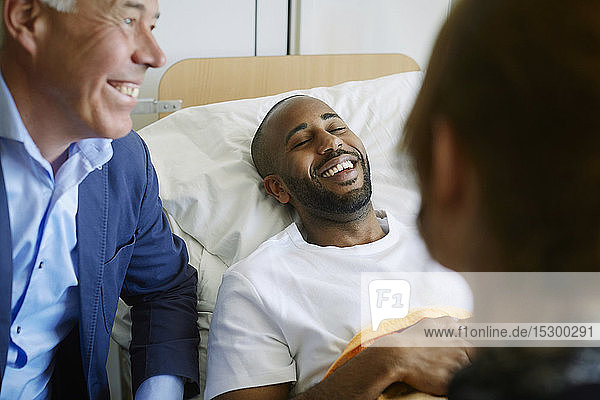 Lächelnder junger Patient mit geschlossenen Augen im Bett liegend auf der Krankenhausstation