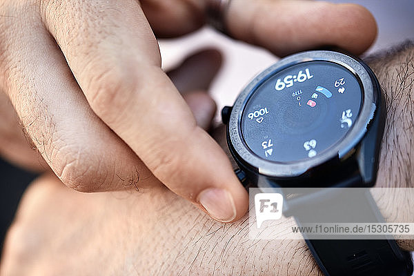 Close-up of man checking data on smartwatch