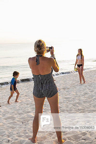 Mutter und ihre Kinder genießen den Strand bei Sonnenuntergang