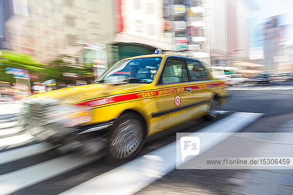 TOKYO  JAPAN ï¾- 06. JUNI 2015: Bewegungsunscharfes gelbes Taxi auf einem Fußgängerüberweg  Tokio  Japan.
