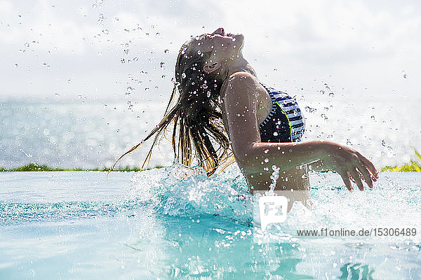 Ein Teenager-Mädchen im Infinity-Pool  das seine Haare zurückwirft