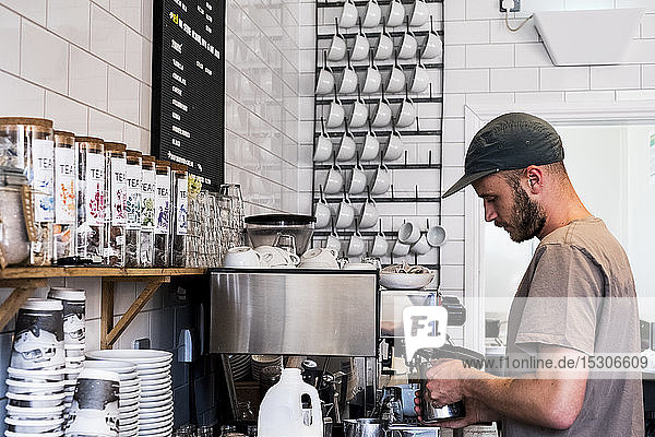 Ein männlicher Barista arbeitet an einer Kaffeemaschine in einem Café.