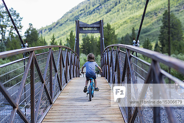 Rückansicht eines 5 Jahre alten Jungen auf einer schmalen Brücke über einen Berg
