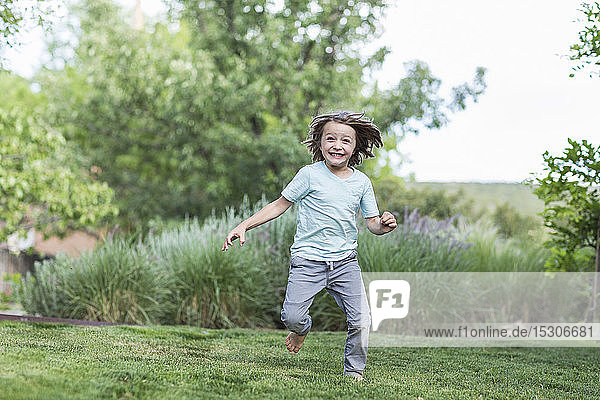 5 Jahre alter Junge läuft auf grünem Rasen