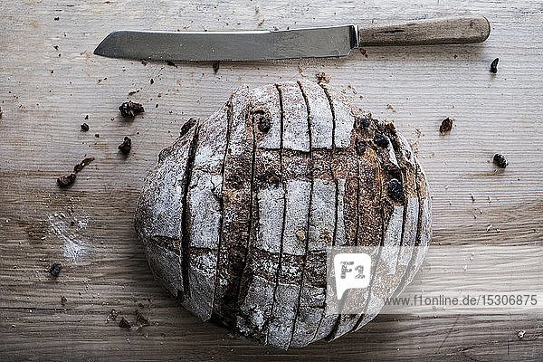 Ein Laib frisch geschnittenes Schwarzbrot auf einem Brotbrett und ein scharfes Messer