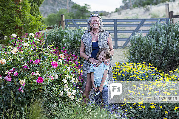 Eine ältere Erwachsene  Großmutter und ihr 5 Jahre alter Enkel beim Rosenschneiden in ihrem Garten