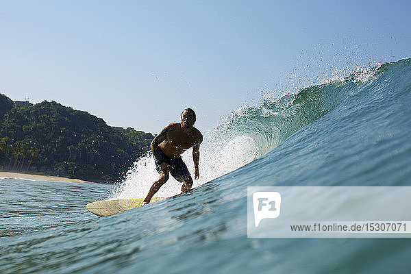 Male surfer riding sunny ocean wave