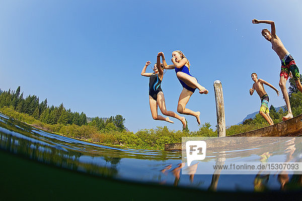 Kinder springen in den sonnigen Sommersee
