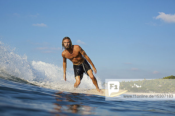 Männlicher Surfer reitet auf einer sonnigen Meereswelle
