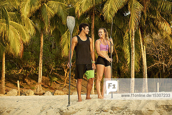 Junges Paar mit Rudern am sonnigen  tropischen Strand