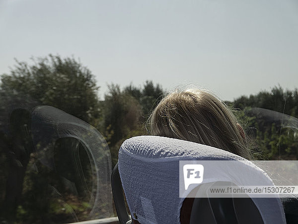 Frau im Zug  die sich entspannt und aus dem sonnigen Fenster schaut