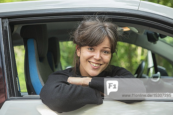 Portrait smiling young woman leaning out car window
